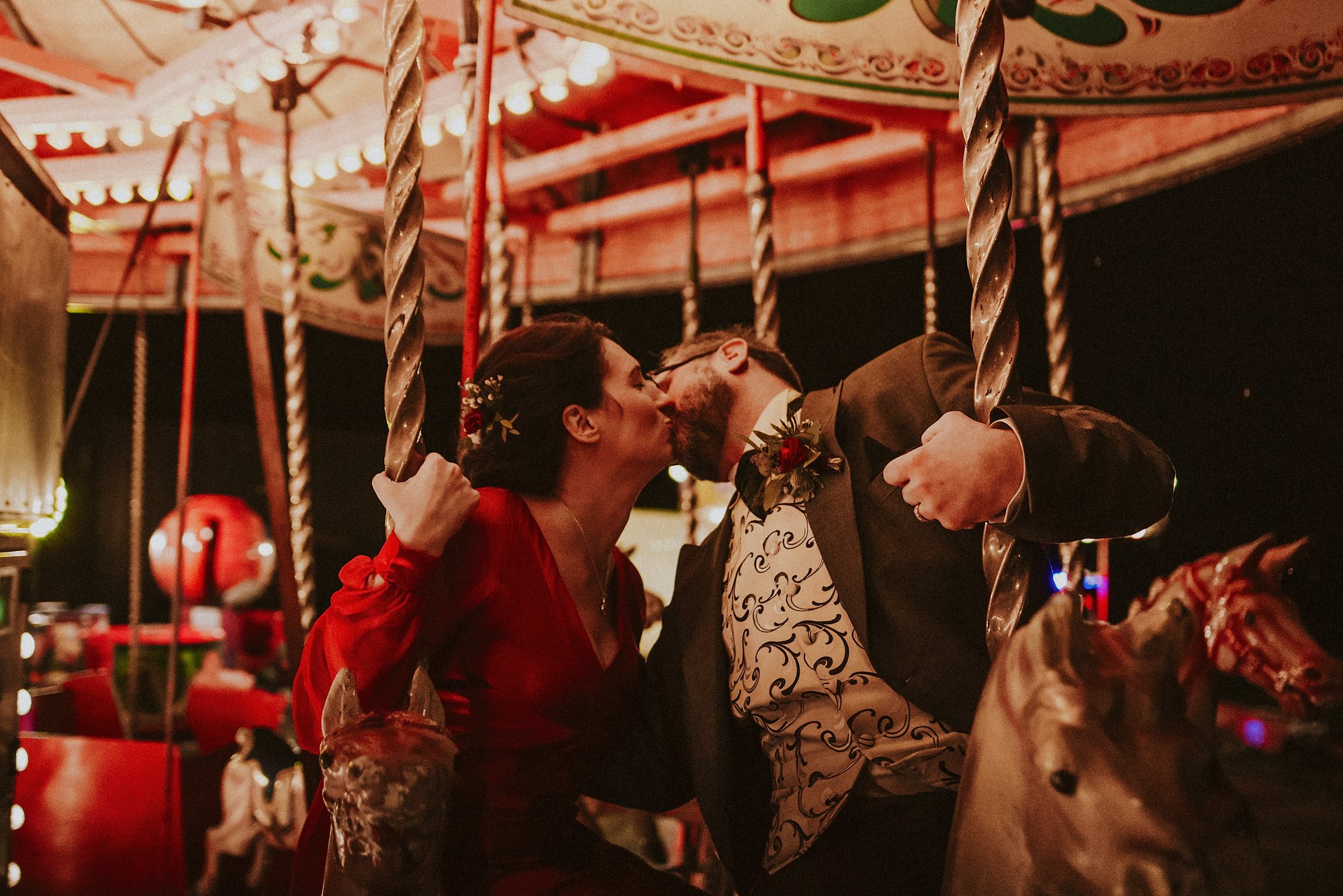Two people riding a carousel and kissing